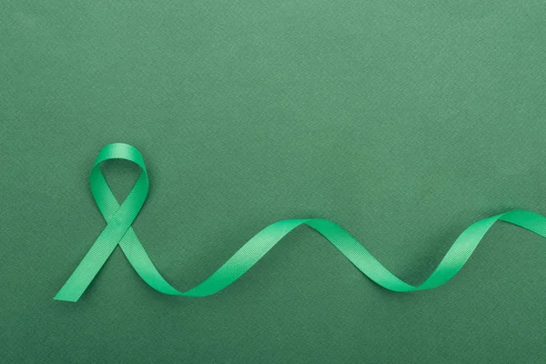 Top view of green and colorful ribbon on green background with copy space — Stock Photo