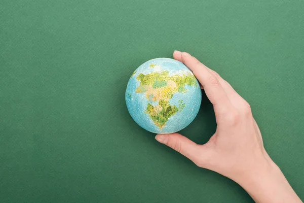 Partial view of woman holding toy earth on green background with copy space — Stock Photo