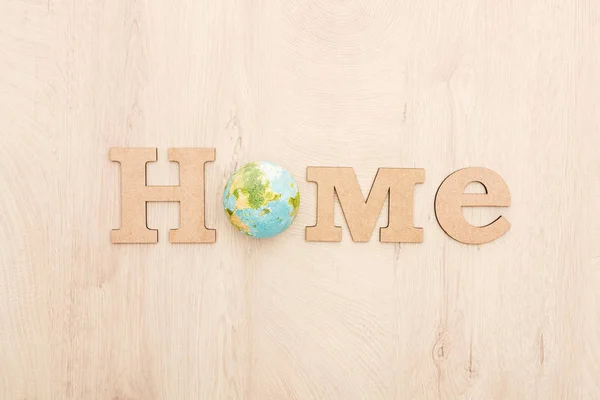 Top view of wooden word home and toy planet on wooden background — Stock Photo