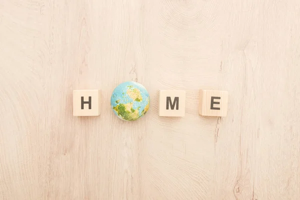 Vista dall'alto di cubi con scritte in casa e pianeta giocattolo su sfondo di legno — Foto stock