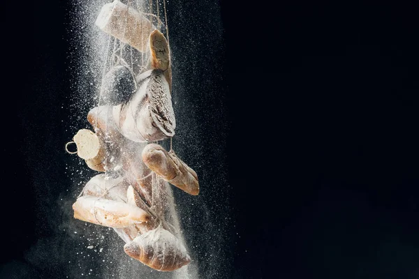 Weißmehl fällt auf Brot an Seilen auf schwarzem Hintergrund mit Kopierraum — Stockfoto