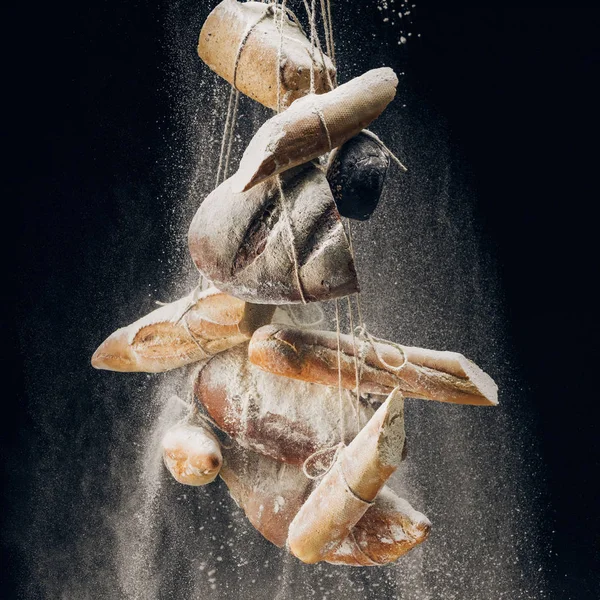 Farinha branca e pão e baguetes em cordas sobre fundo preto — Fotografia de Stock