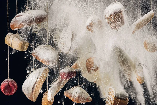 Flour falling at fresh bread and pastry hanging on ropes — Stock Photo