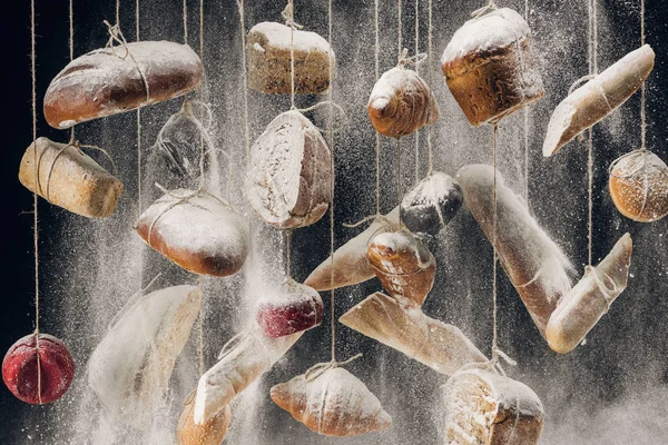 Flour falling at fresh homemade bread hanging on ropes — Stock Photo