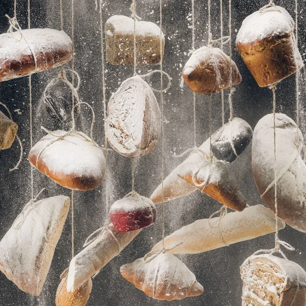 Flour falling at homemade bread and pastry hanging on ropes — Stock Photo