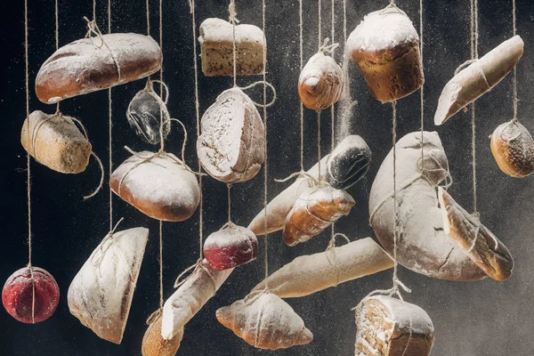 Flour falling at fresh homemade bread and pastry hanging on ropes — Stock Photo