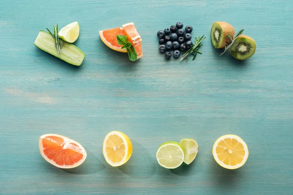 Draufsicht auf saftige Früchte und Blaubeeren auf blau strukturierter Oberfläche — Stockfoto