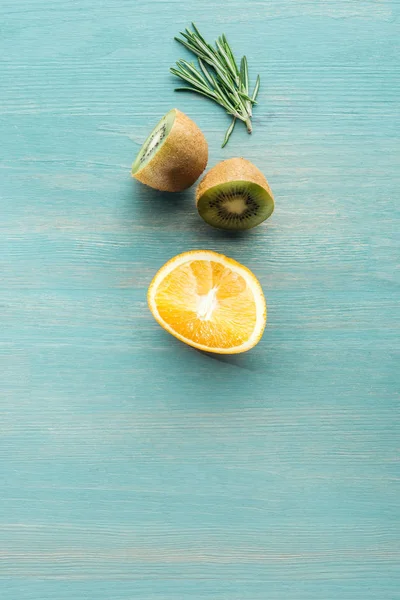 Vista superior de frutas cortadas y romero sobre superficie texturizada azul - foto de stock