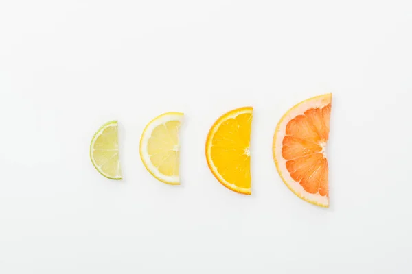 Acostado plano con naranja cortada, limón, lima y pomelo sobre una superficie blanca — Stock Photo