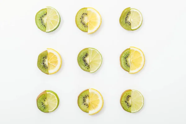 Poser à plat avec des citrons coupés, des citrons verts et des kiwis sur la surface blanche — Photo de stock