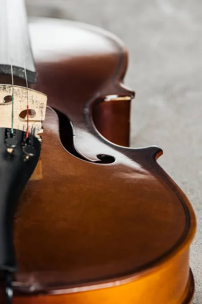 Nahaufnahme eines klassischen hölzernen Cellos auf grau strukturiertem Hintergrund — Stockfoto