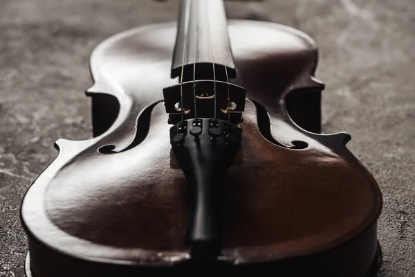 Close up de violoncelo de madeira clássica em fundo cinza texturizado na escuridão — Fotografia de Stock