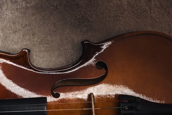 Vista superior del violonchelo de madera clásico sobre la superficie texturizada gris en la oscuridad - foto de stock