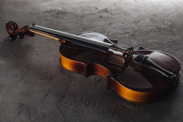 Wooden classic violoncello in darkness on textured surface — Stock Photo