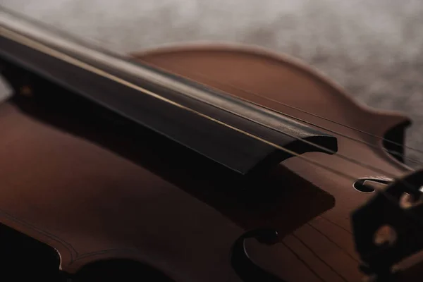 Nahaufnahme von Streichern auf hölzernem Violoncello in der Dunkelheit auf grau strukturiertem Hintergrund — Stockfoto