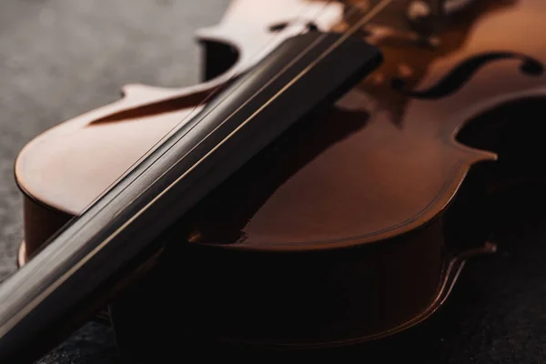 Nahaufnahme von Streichern auf Violoncello in Dunkelheit auf grau strukturiertem Hintergrund — Stockfoto