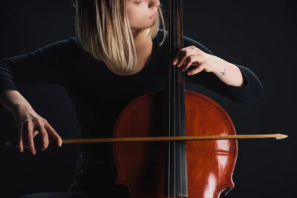 Vue partielle de femme tatouée jouant de la contrebasse dans l'obscurité isolé sur noir — Photo de stock