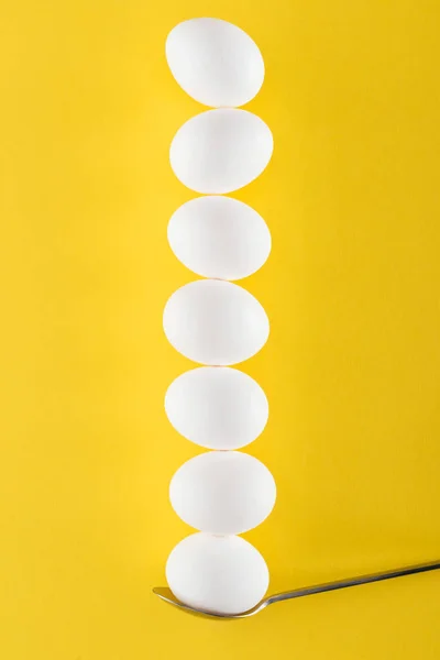 Seven white chicken eggs on spoon on yellow background — Stock Photo