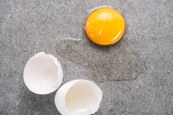 Close up de ovo cru esmagado com gema de ovo e proteína em fundo cinza — Fotografia de Stock
