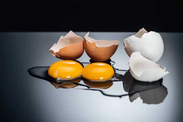 Raw smashed chicken eggs with yolks, proteins and eggshell isolated on black — Stock Photo