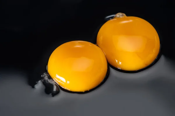 Close up of raw chicken yolks and proteins on black background — Stock Photo