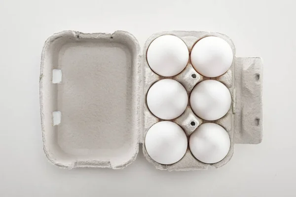Вид зверху сирих білих курячих яєць у картонній коробці на білому тлі — стокове фото