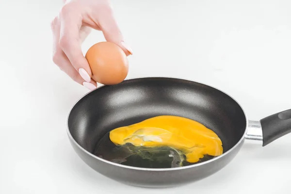 Cropped view of woman preparing scrambled eggs in pan on white background — Stock Photo