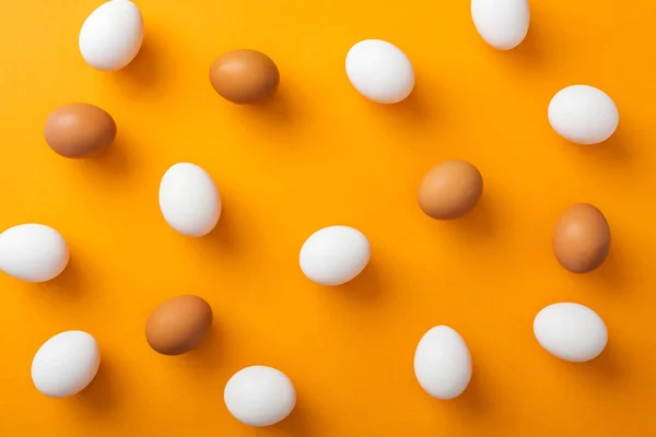 Top view of whole white and brown organic chicken eggs on bright orange background — Stock Photo