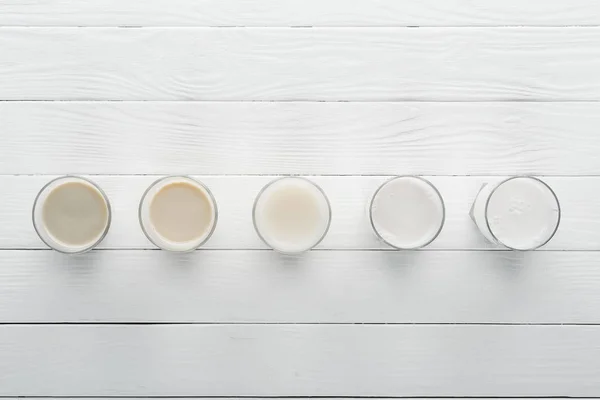 Top view of different types of milk on white wooden surface — Stock Photo