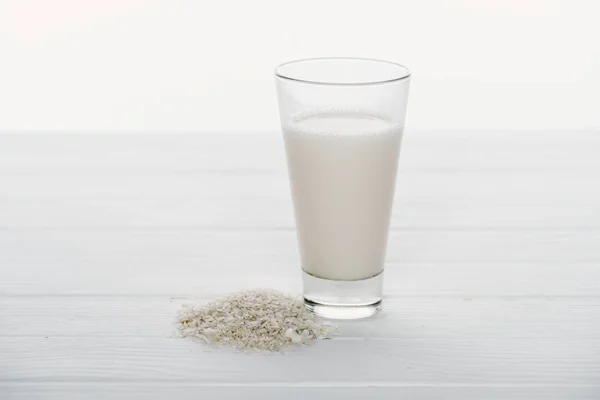 Rice milk in glass near rice grains on wooden table isolated on white — Stock Photo