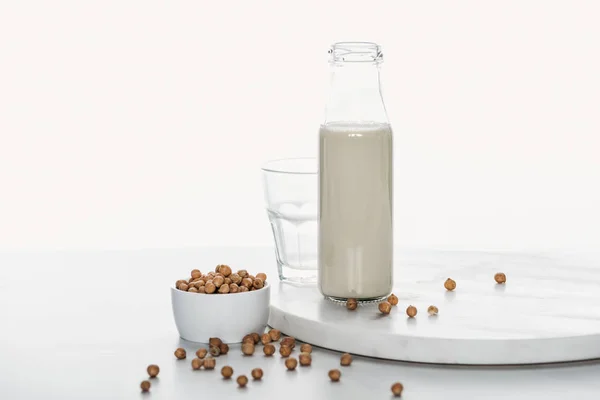 Chickpea milk in bottle near chickpea in bowl and empty glass isolated on white — Stock Photo