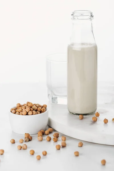 Lait végétalien de pois chiche en bouteille près de pois chiche dans un bol et verre vide isolé sur blanc — Photo de stock