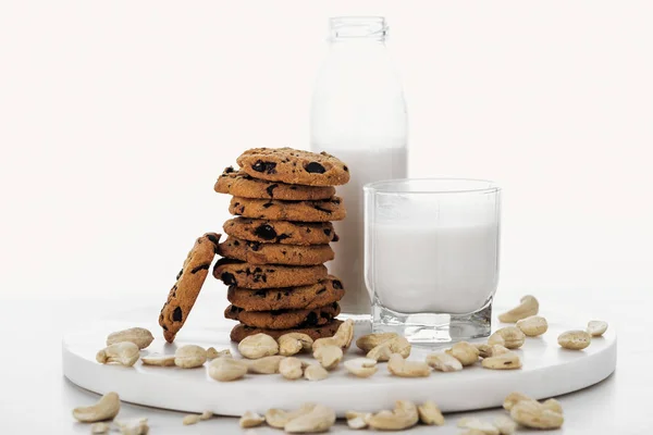 Vegan cashew milk in glass and bottle near chocolate cookies isolated on white — Stock Photo