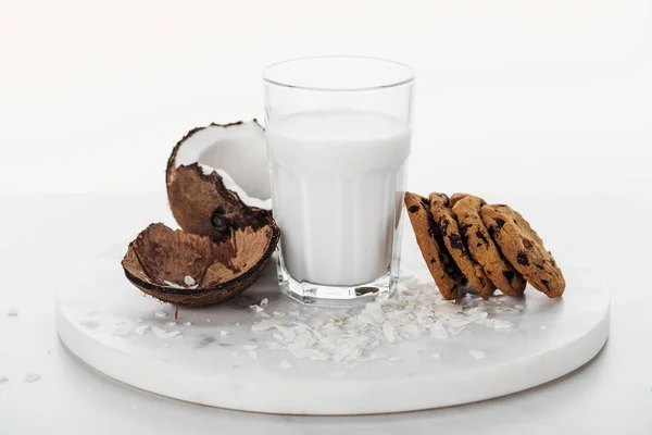 Lait de coco végétalien en verre près de la noix de coco et biscuits au chocolat isolés sur blanc — Photo de stock