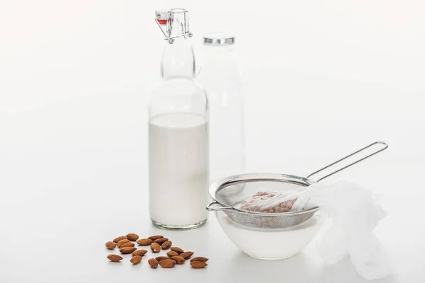 Fresh almond and chickpea vegan milk in bowl and bottle near ingredients — Stock Photo