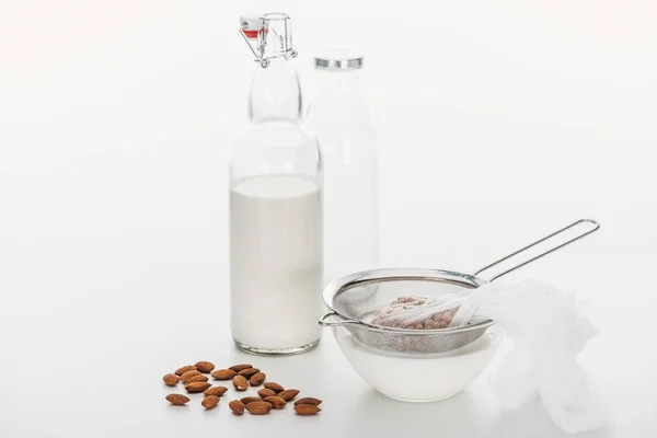 Leche vegana de almendras y garbanzos frescos en tazón y botella cerca de los ingredientes - foto de stock