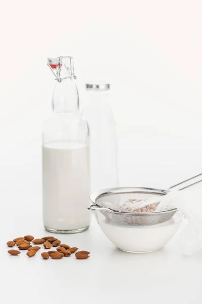 Leche vegana de almendras y garbanzos en tazón y botella cerca de los ingredientes - foto de stock