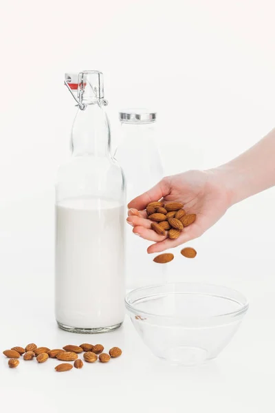 Vista recortada de la mujer poniendo almendras en un tazón mientras cocina leche vegana de almendras - foto de stock