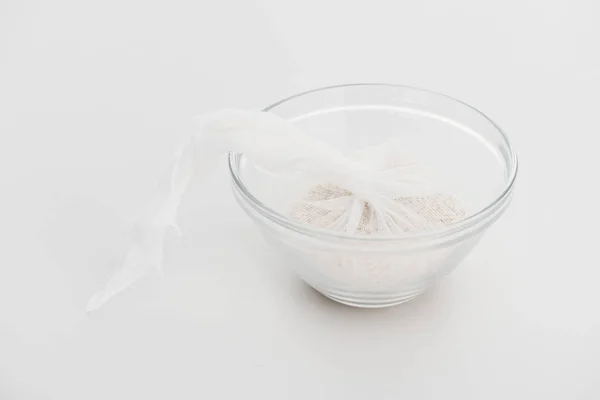 Rice in cheesecloth in glass bowl on grey background — Stock Photo