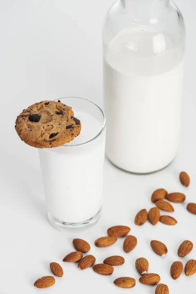 Органічне мигдальне молоко в пляшці і склянці з шоколадним печивом і розкиданим мигдалем — стокове фото