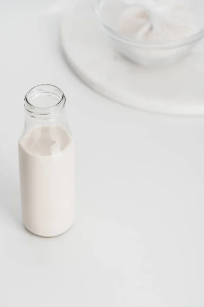 Selective focus of rice milk in bottle with rice in cheesecloth on background — Stock Photo