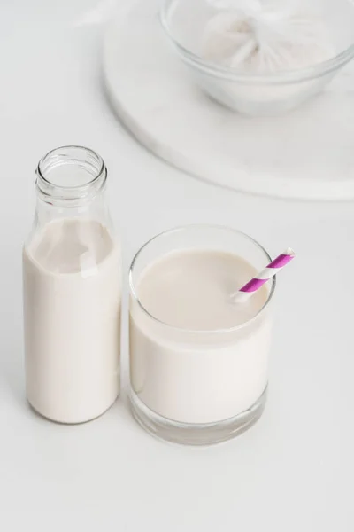 Enfoque selectivo de la leche de arroz en botella y vaso con arroz en mantel de queso en el fondo - foto de stock