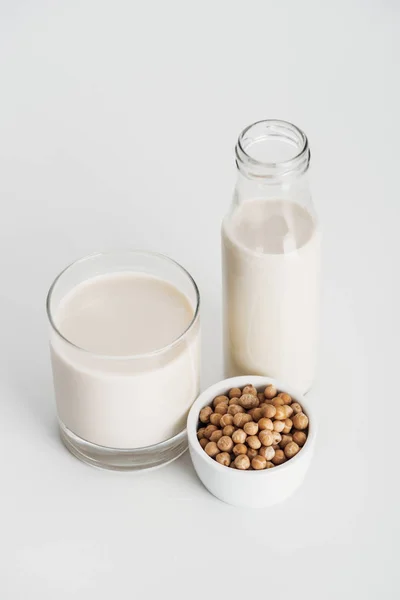 Pois chiche dans un bol près du lait végétalien de pois chiche sur fond gris — Photo de stock