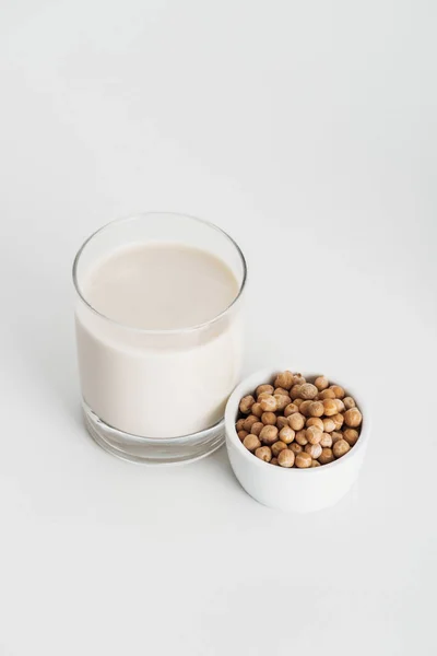 Chickpea in bowl near vegan chickpea milk in glass on grey background — Stock Photo