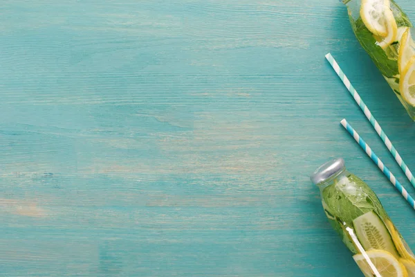Vue de dessus de boisson de désintoxication avec citron, menthe et concombre en bouteilles près de pailles — Photo de stock