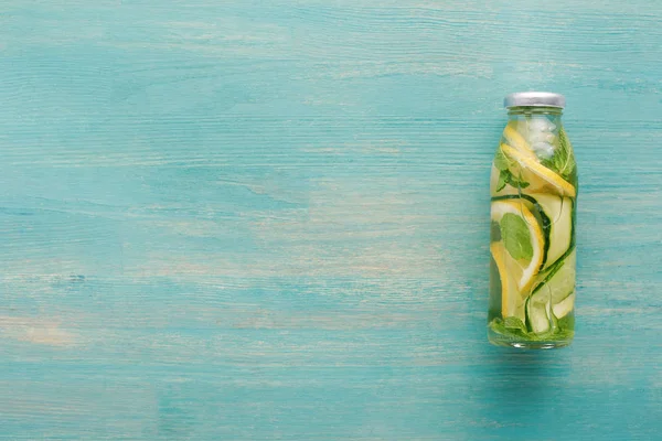 Вид на детоксикационный напиток в бутылке со свежими ломтиками лимона и огурца и мятой — стоковое фото