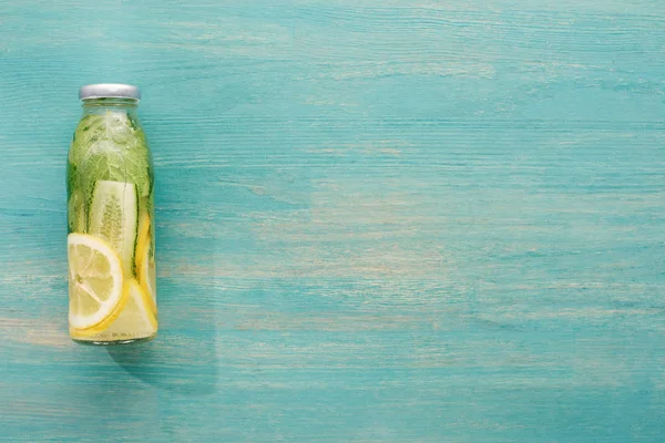Top view of detox drink in bottle with fresh lemon and cucumber slices and green mint — Stock Photo