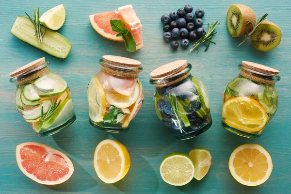 Vista superior de bebidas de desintoxicação em frascos com ingredientes de frutas na superfície de madeira — Fotografia de Stock