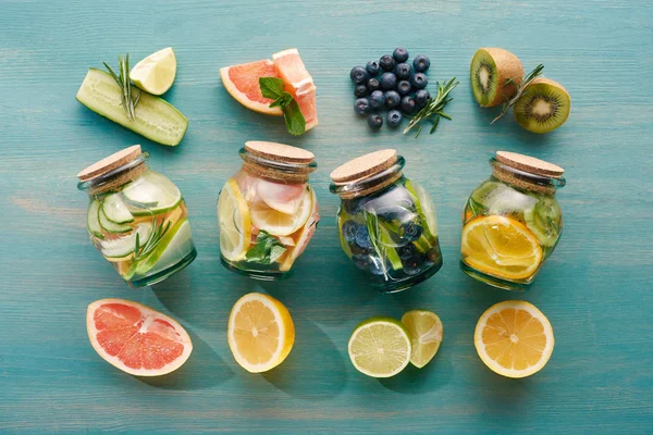 Vista superior de bebidas de desintoxicação em jarros com frutas cítricas, bagas e pepinos — Fotografia de Stock