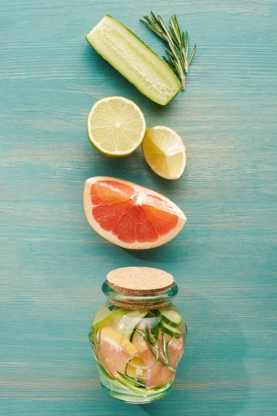 Top view of detox drink in jar with lemons, limes, grapefruits, cucumbers and rosemary — Stock Photo
